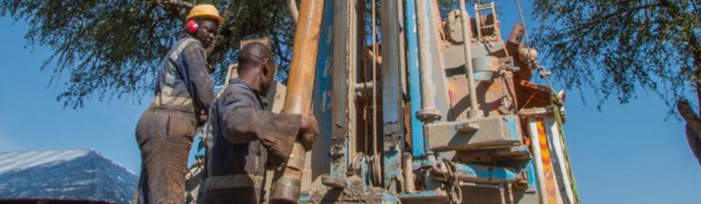 Drilling crew handling pipe at a water well rig